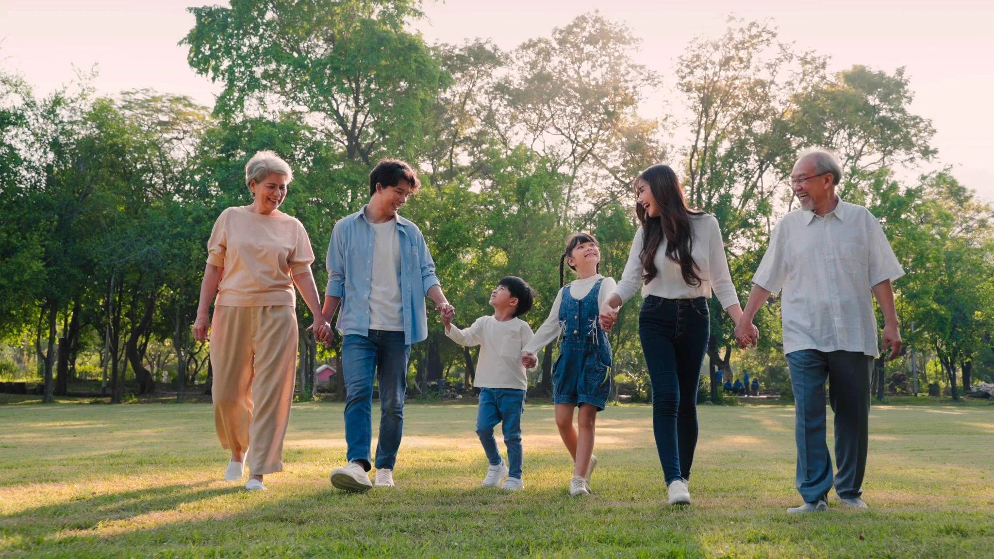 Three generations of a family walking hand in hand across a park